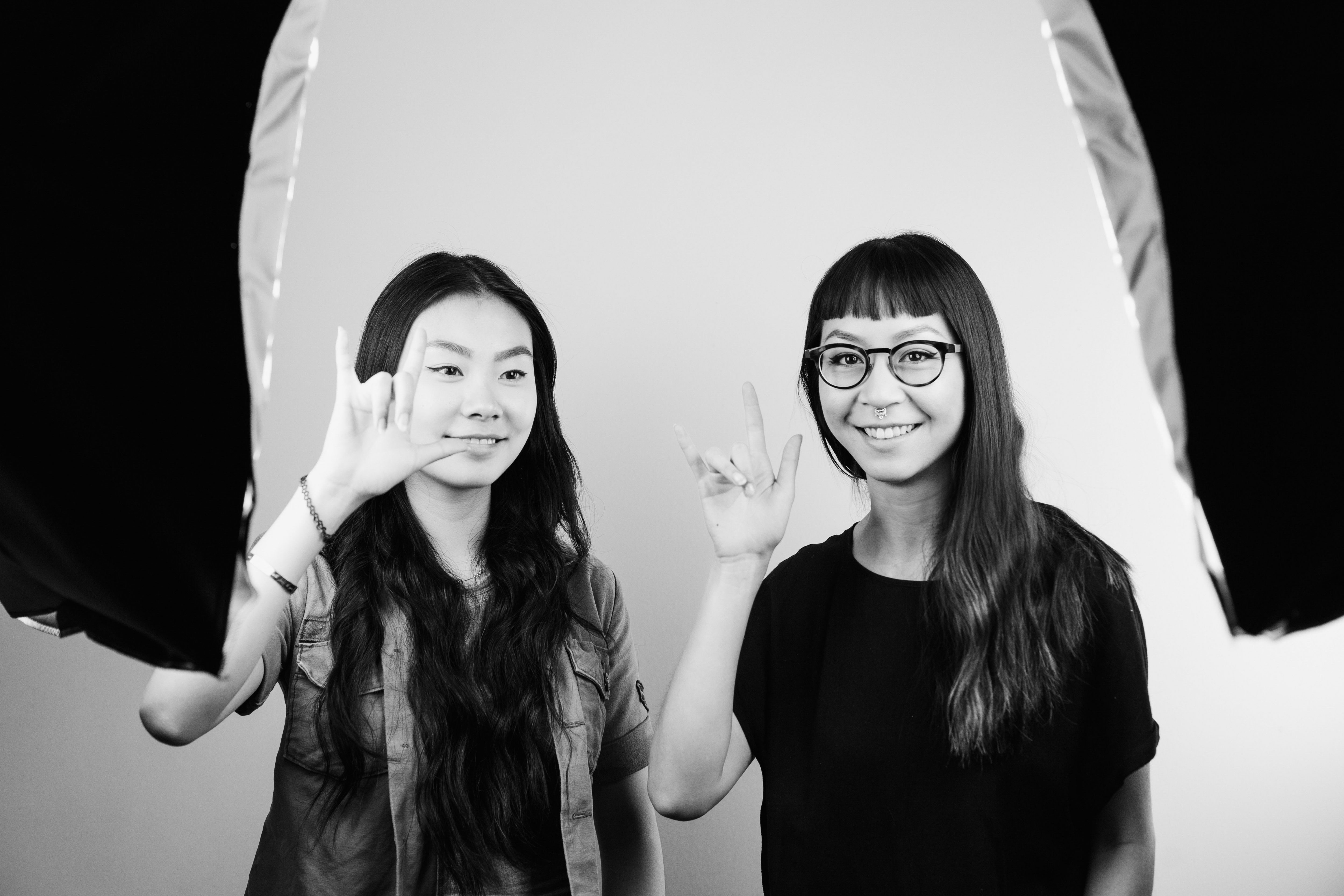 Black and white image of two Hangar 18 twinterns gesturing the rock 'n' roll sign with their right hand