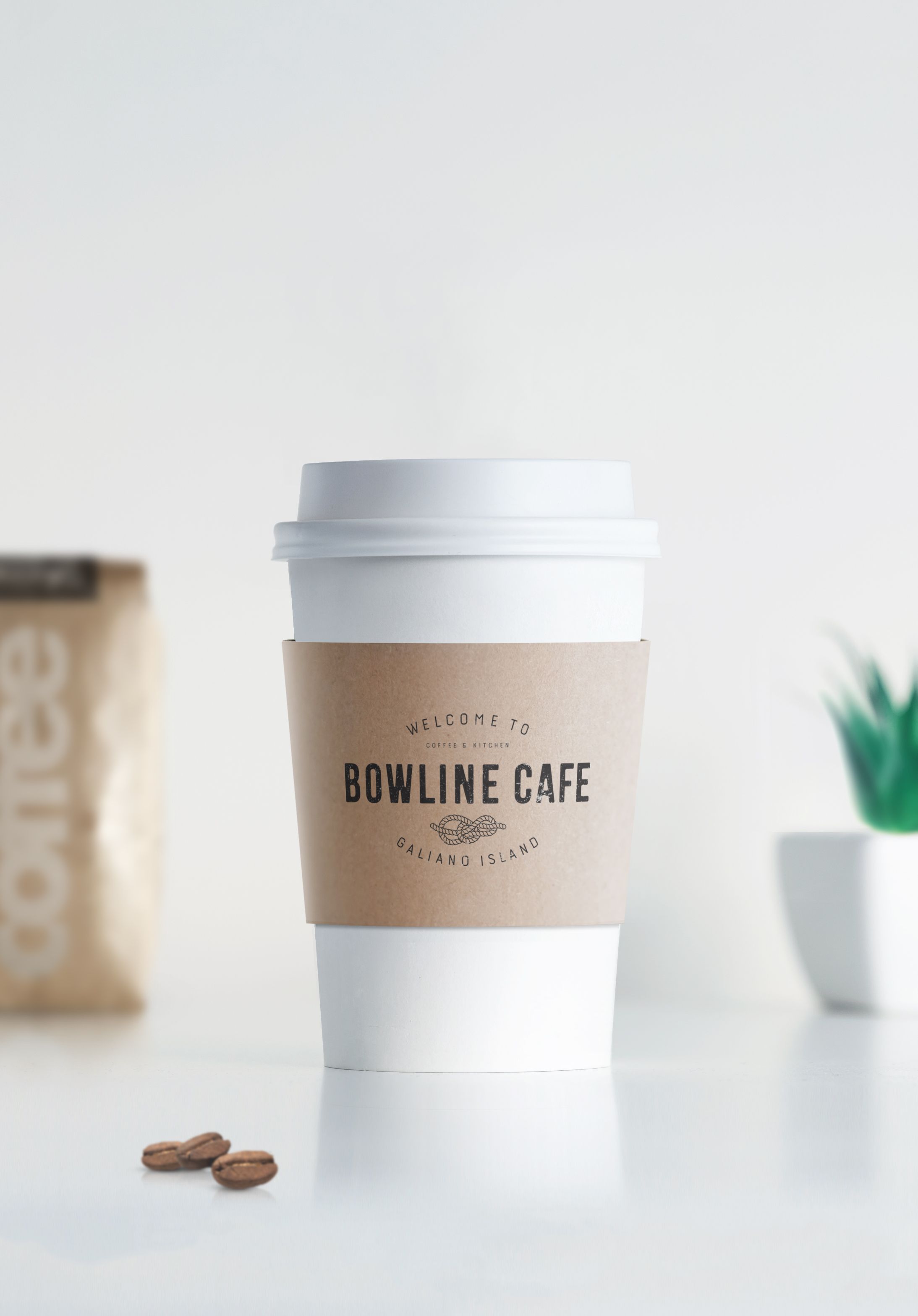 A brown coffee sleeve with the Bowline Logo on a white coffee cup